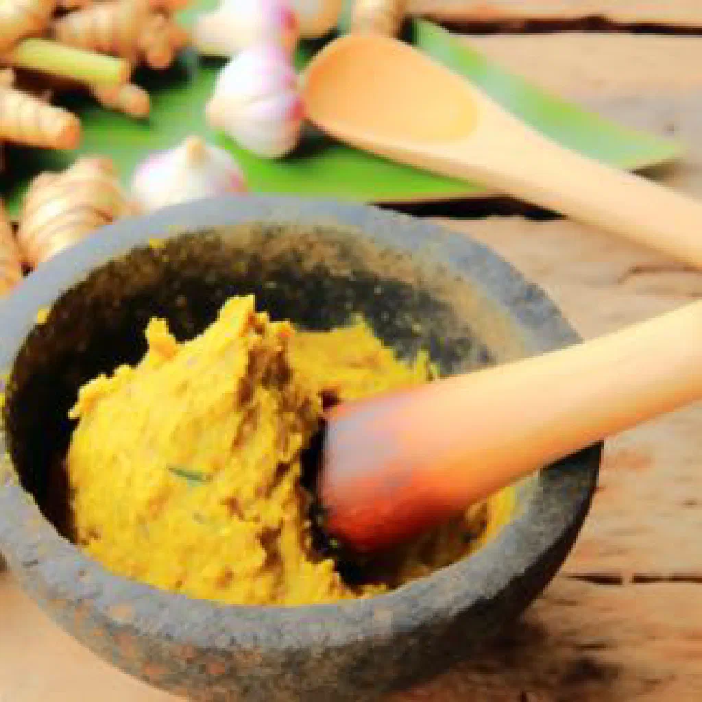 A vibrant yellow bowl of Cambodian kroeung spice paste garnished with fresh coriander