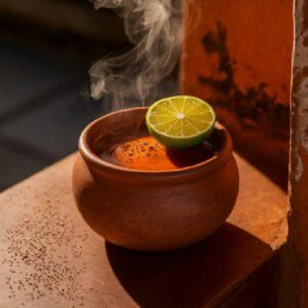 Glass of aguapanela con limón with ice and fresh lime slices
