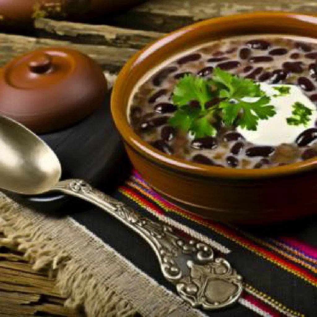 A bowl of Costa Rican black beans garnished with fresh coriander and lime