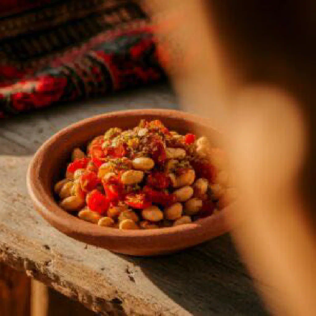 Creamy Eritrean shahan ful topped with fresh tomatoes and herbs
