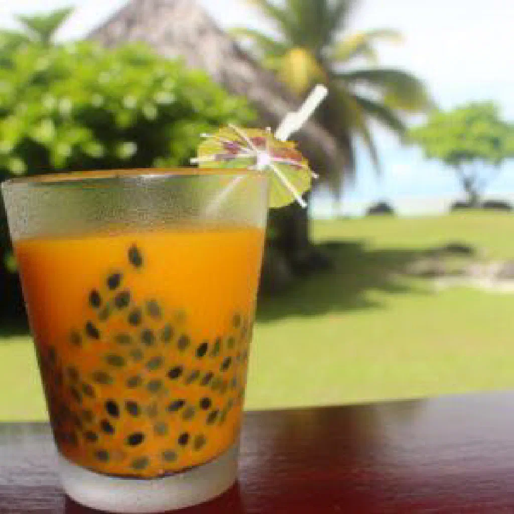 A glass of fresh Fijian passion fruit juice garnished with mint and lime