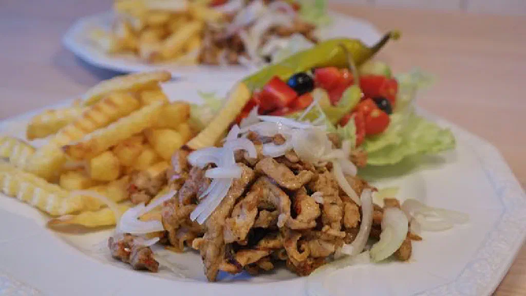 Greek gyros with grilled spiced meat, onions and tomato in pita bread