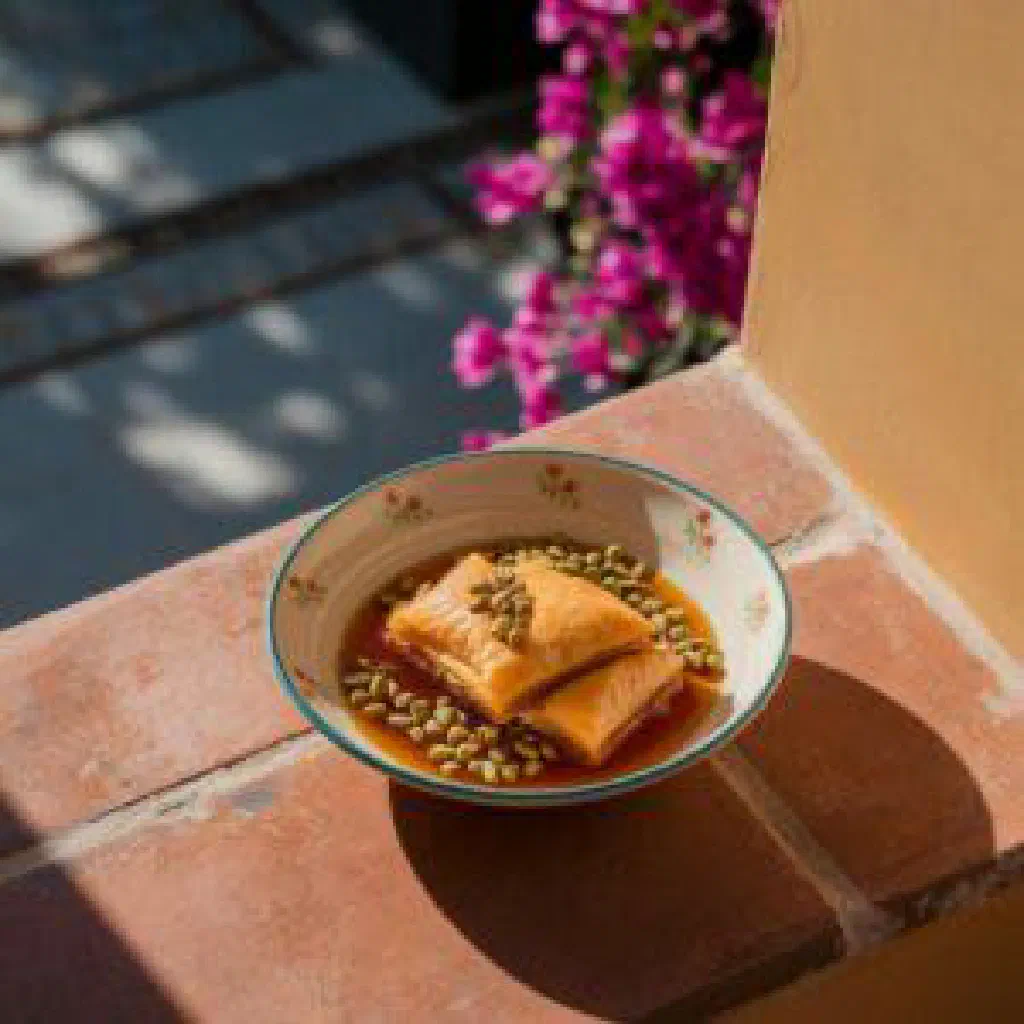 Golden Greek zacharoplasteio cake dusted with sugar on a plate
