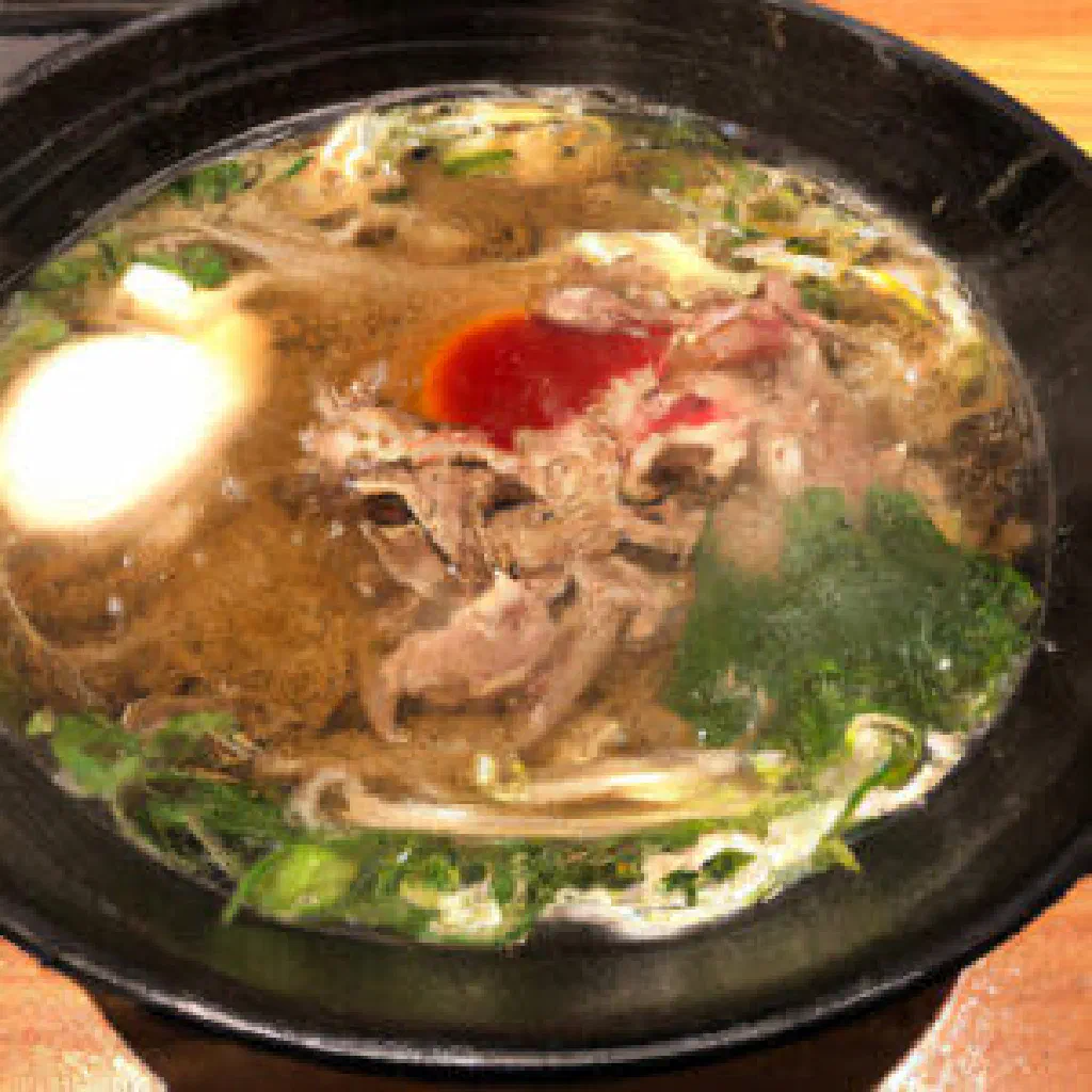 Sukiyaki hot pot with sliced beef, tofu, spring onions and shiitake in a sweet soy broth