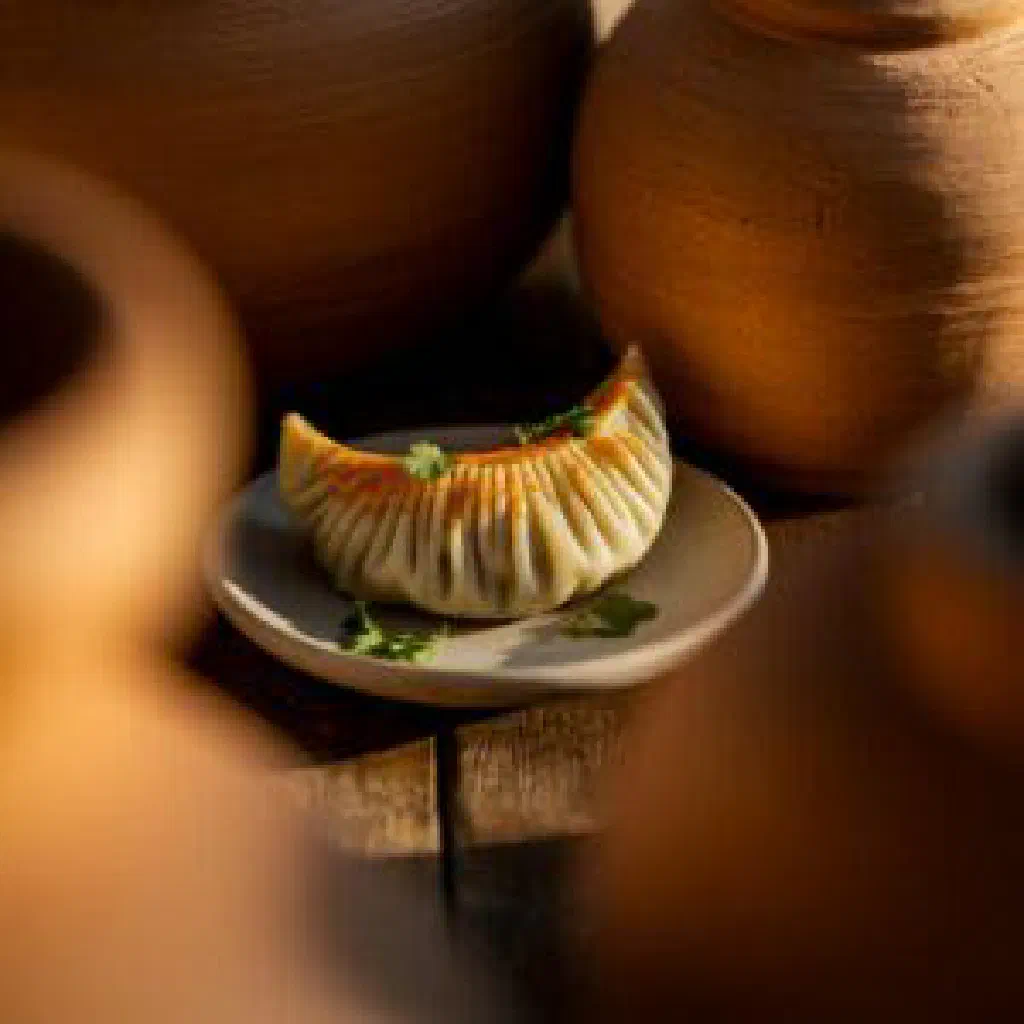 Small Kyrgyz chuchvara dumplings served in a clear broth with fresh herbs