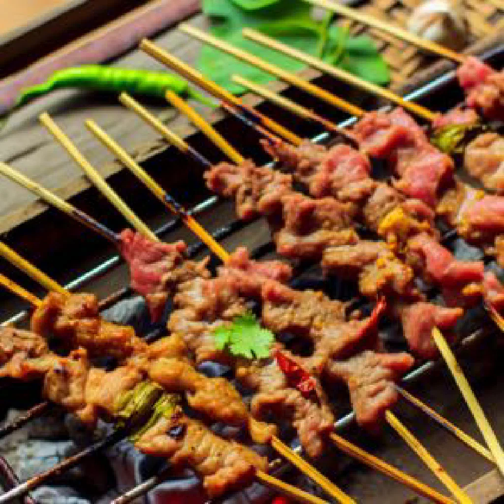 Grilled Lao pork skewers served with fresh herbs and lettuce