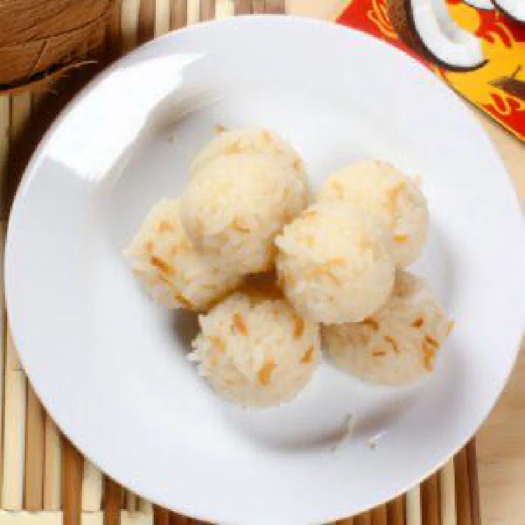 Coconut rice balls arranged on a plate with grated coconut