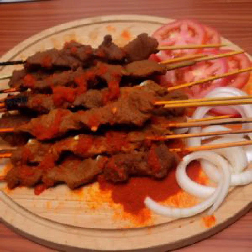 Grilled suya skewers coated in spicy peanut rub with onion rings