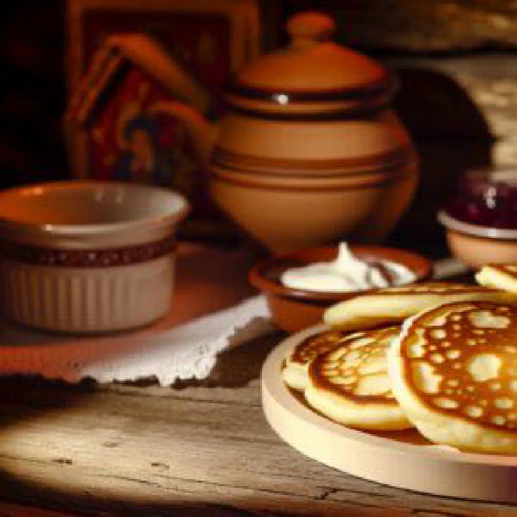 A stack of fluffy golden oladyi pancakes dusted with sugar