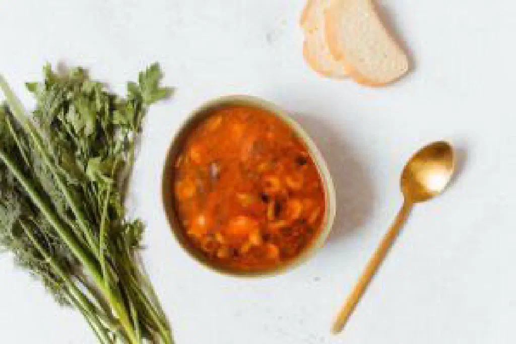 Bowl of hearty solyanka soup with soured cream, olives and fresh dill