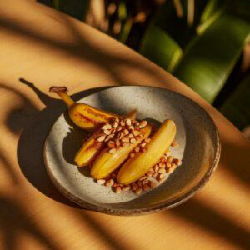 Sliced ripe bananas topped with chopped roasted peanuts in a bowl