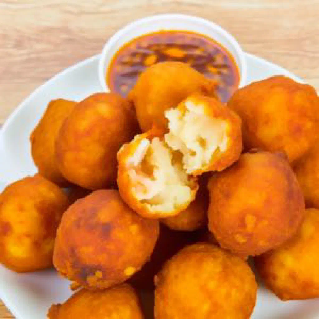 Golden fried yam balls served on a plate with fresh herbs