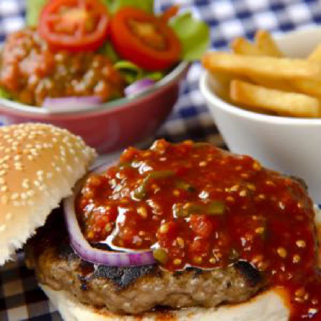 Beef burger topped with glossy monkey gland sauce in a soft bun