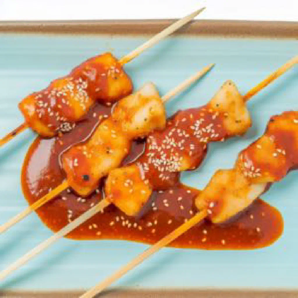Sweet Korean rice cakes on bamboo skewers sprinkled with sesame seeds