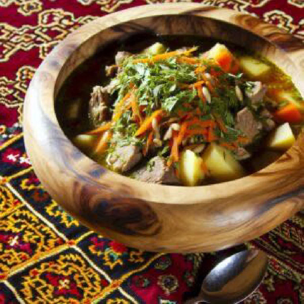 Bowl of Tajik shurbo with lamb, chickpeas and vegetables, garnished with coriander