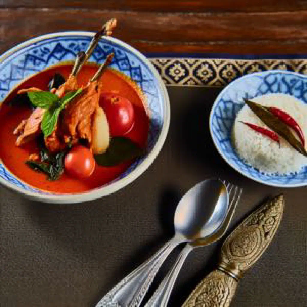 Thai red curry with roasted duck, coconut milk and fresh herbs in a bowl