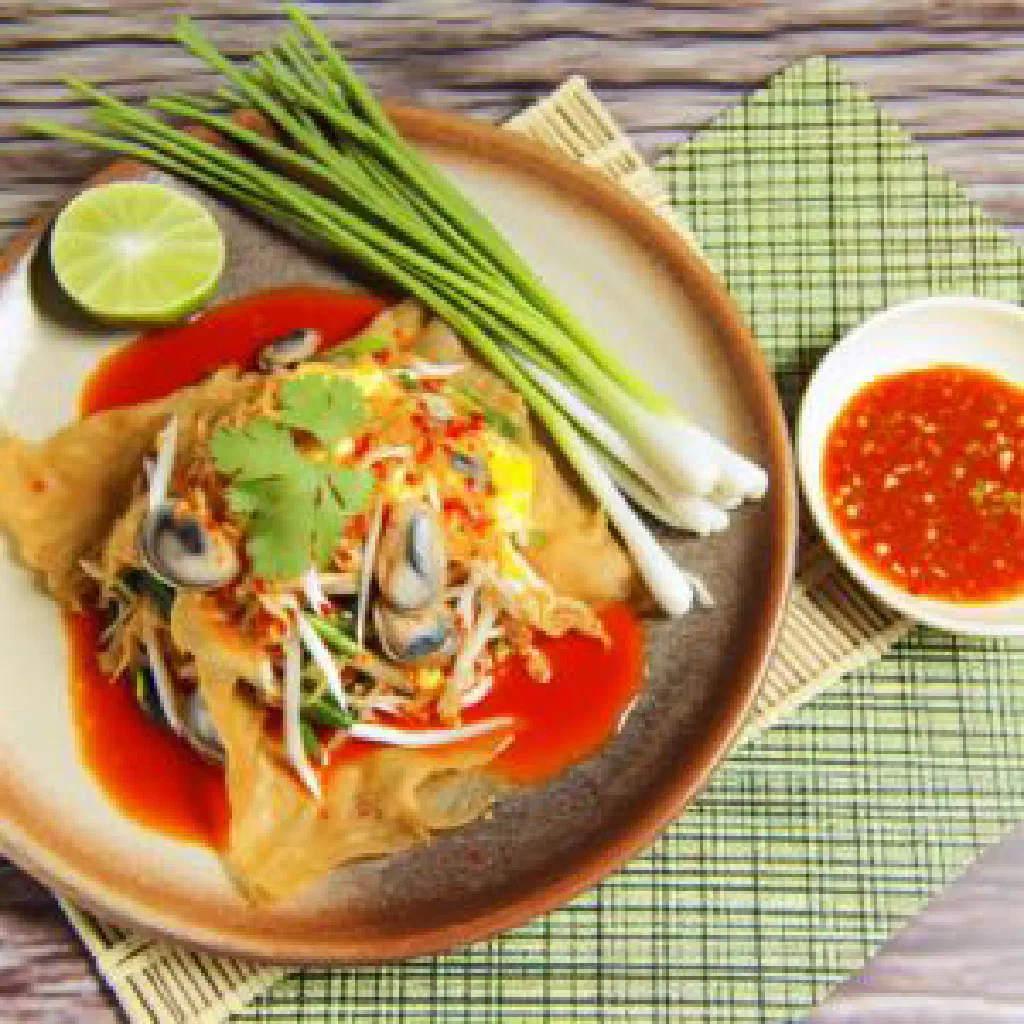 Crispy Thai mussel pancake garnished with fresh coriander and lime