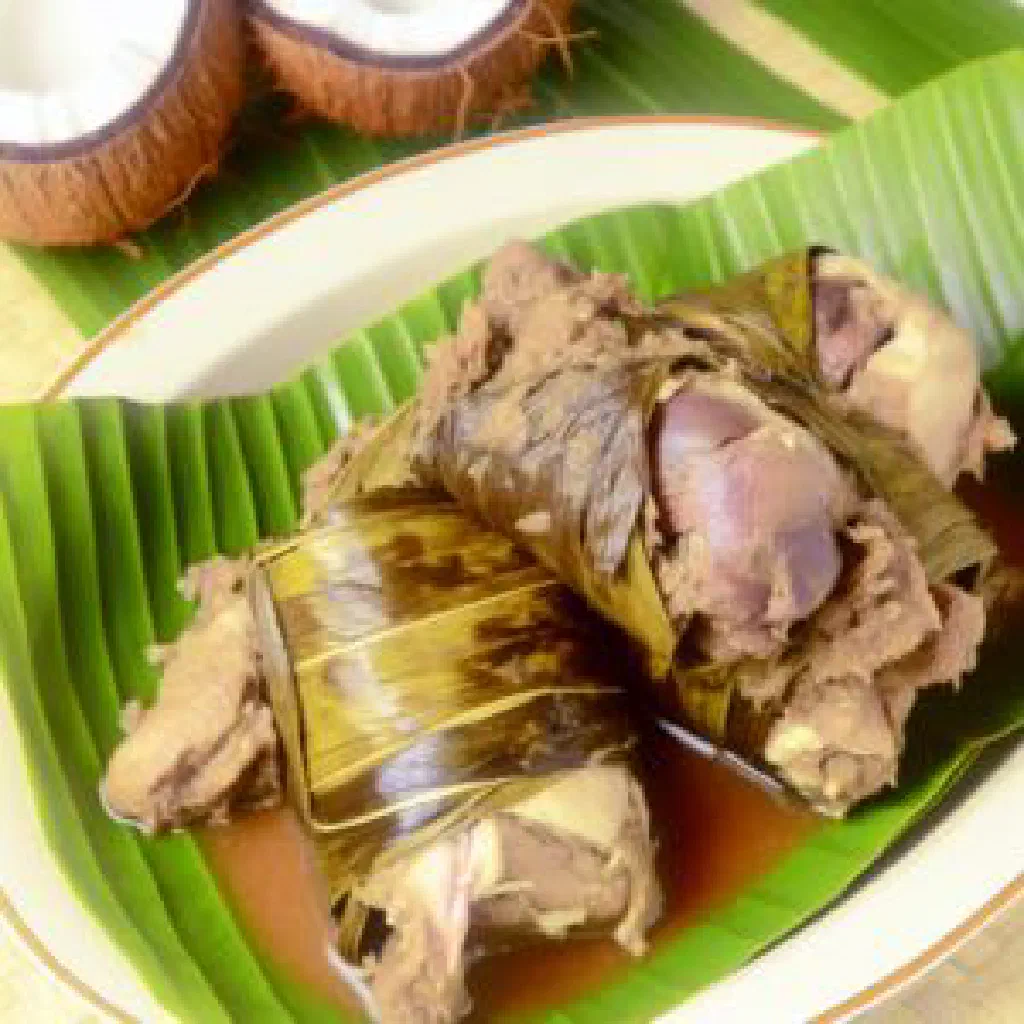 Tender chicken simmered with taro leaves in coconut milk, served in a bowl