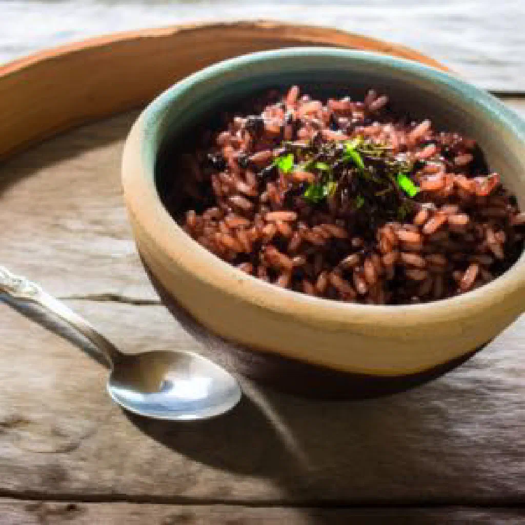 Bowl of cocoa rice garnished with fresh herbs