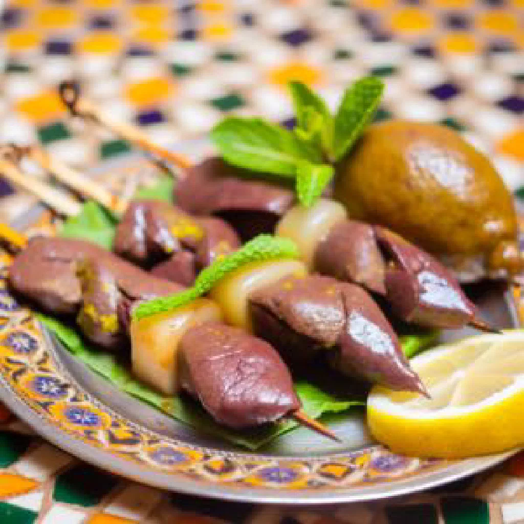 Grilled Tunisian boulfaf mutton skewers with lemon wedges