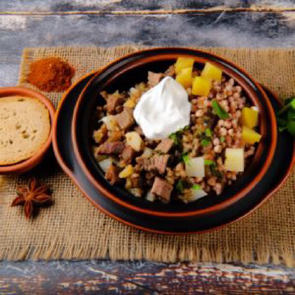 Bowl of creamy Ukrainian kulesha topped with a knob of butter and fresh herbs