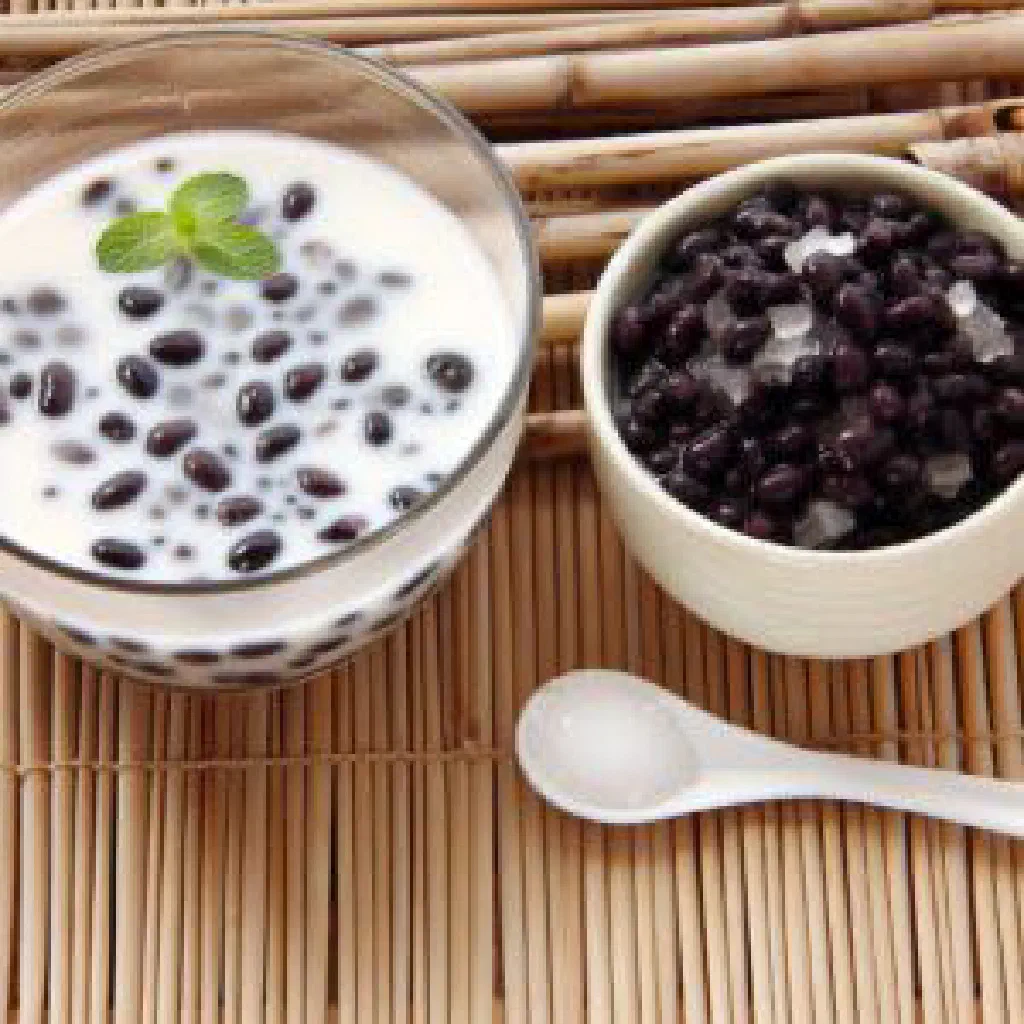 A bowl of Che Dau Den sweet black bean dessert topped with coconut milk